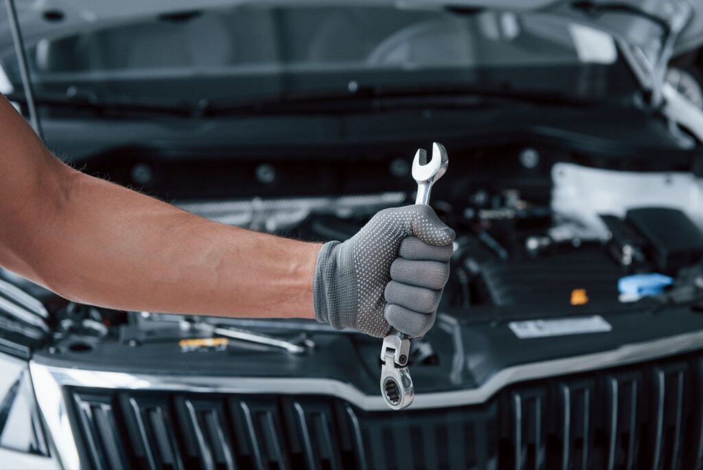 Man's hand in glove holds wrench